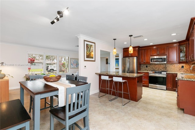 kitchen with sink, light stone counters, tasteful backsplash, decorative light fixtures, and stainless steel appliances