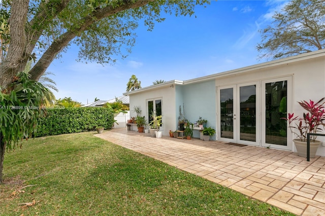 rear view of property featuring a patio, a yard, and french doors