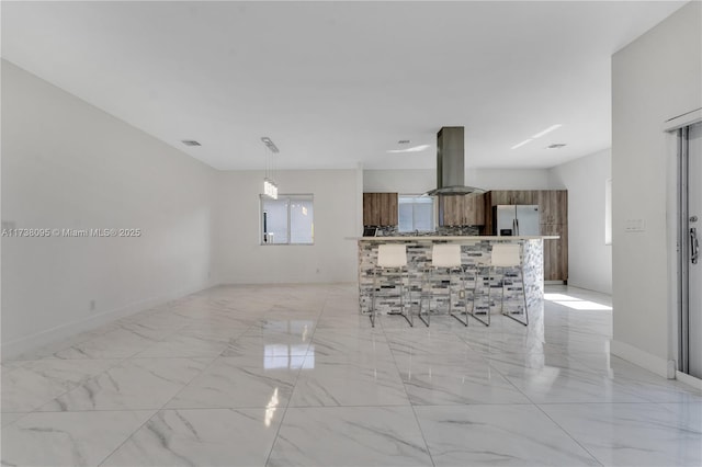 kitchen featuring stainless steel fridge with ice dispenser, a kitchen breakfast bar, hanging light fixtures, and island exhaust hood