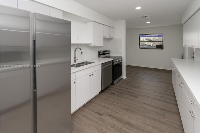 kitchen featuring tasteful backsplash, visible vents, dark wood finished floors, appliances with stainless steel finishes, and a sink