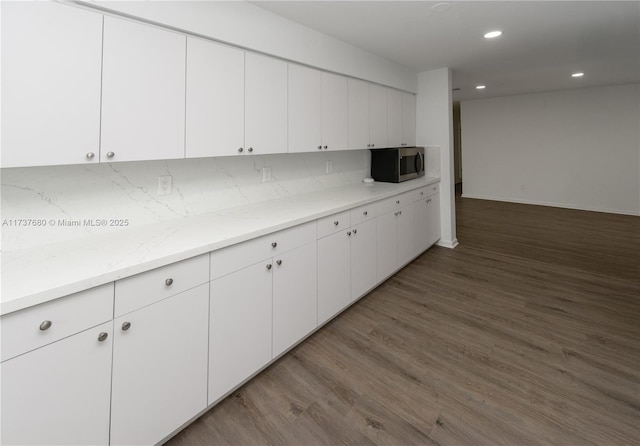 kitchen with white cabinets, stainless steel microwave, wood finished floors, backsplash, and recessed lighting