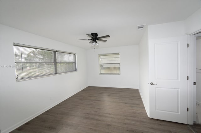 unfurnished room featuring a ceiling fan, visible vents, baseboards, and wood finished floors