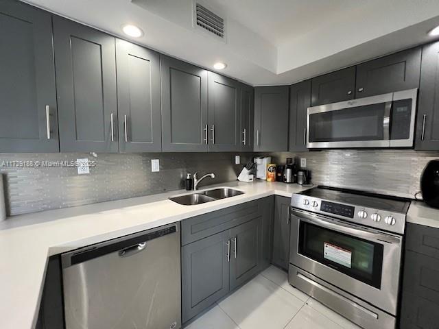 kitchen with appliances with stainless steel finishes, sink, and decorative backsplash