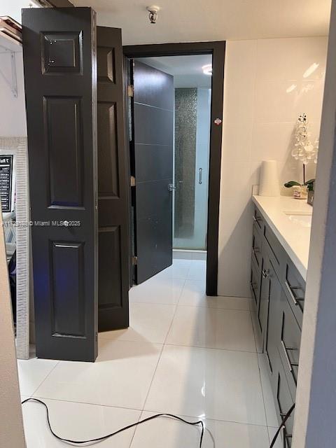 bathroom featuring vanity, a shower with shower door, and tile patterned flooring