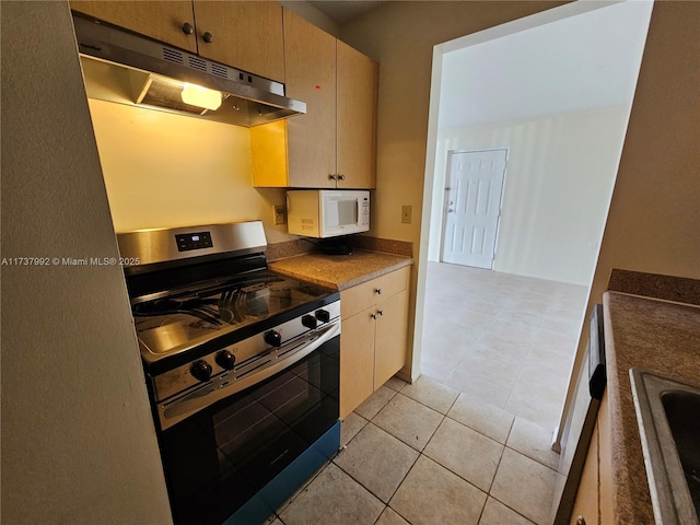 kitchen featuring light brown cabinetry, light tile patterned floors, sink, and stainless steel range oven