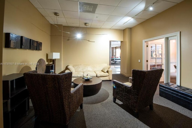 carpeted living room featuring a drop ceiling