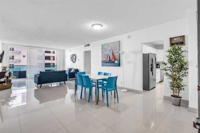 dining room featuring visible vents, baseboards, light tile patterned floors, and a textured ceiling