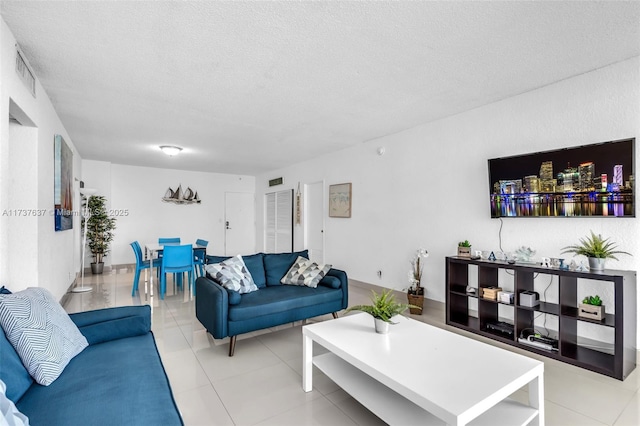 living area featuring a textured ceiling, light tile patterned floors, and visible vents