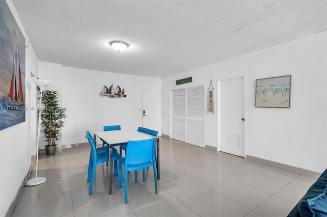 tiled dining area with a textured ceiling and baseboards