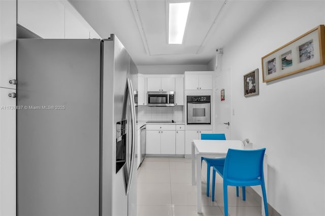 kitchen with light tile patterned flooring, decorative backsplash, white cabinetry, and stainless steel appliances