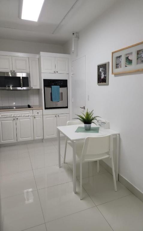 kitchen featuring white cabinetry, appliances with stainless steel finishes, light tile patterned floors, and decorative backsplash