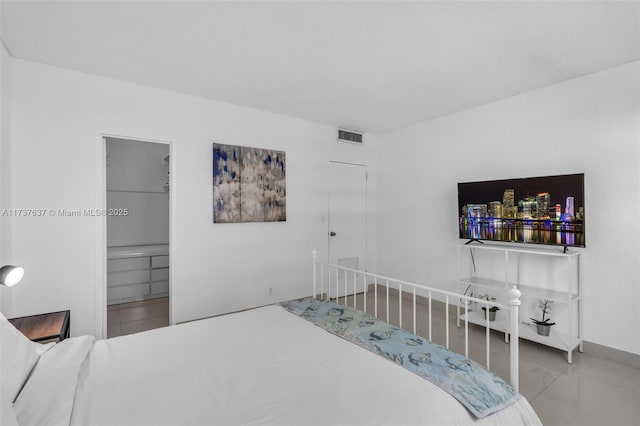 tiled bedroom with a walk in closet