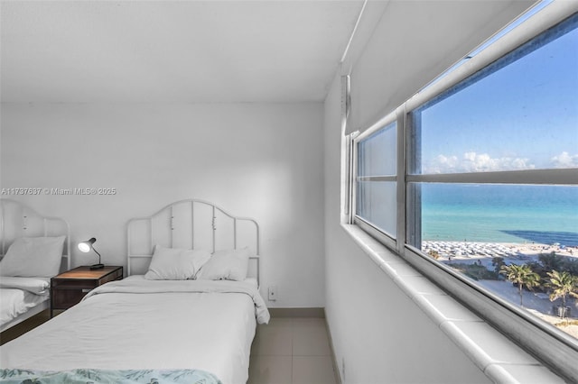 tiled bedroom featuring a water view and baseboards