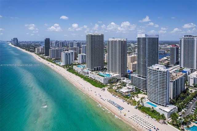 drone / aerial view featuring a water view, a city view, and a view of the beach