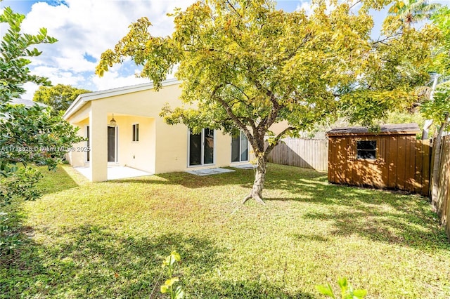 back of property featuring a storage shed, a yard, and a patio area