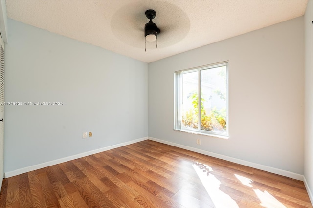 empty room featuring wood-type flooring, ceiling fan, and a textured ceiling