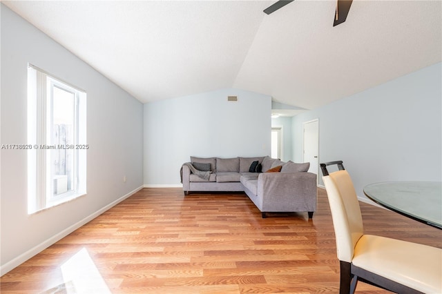 living room featuring light hardwood / wood-style flooring, vaulted ceiling, and ceiling fan