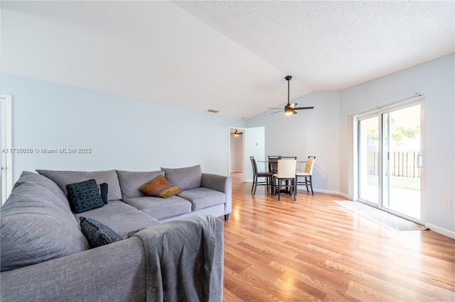 living room featuring ceiling fan, lofted ceiling, a textured ceiling, and light wood-type flooring