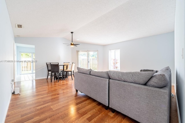 living room with vaulted ceiling, plenty of natural light, hardwood / wood-style floors, and a textured ceiling