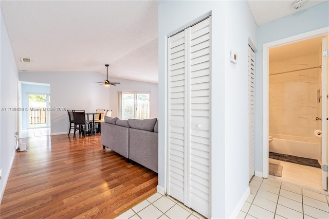 corridor featuring vaulted ceiling, light hardwood / wood-style flooring, and a wealth of natural light