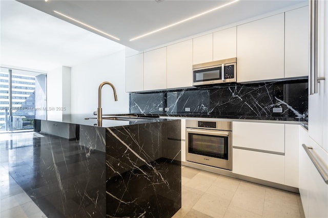 kitchen featuring white cabinetry, a wall of windows, stainless steel appliances, and backsplash