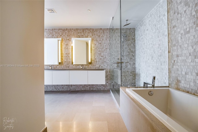 bathroom with vanity, shower with separate bathtub, and tile walls