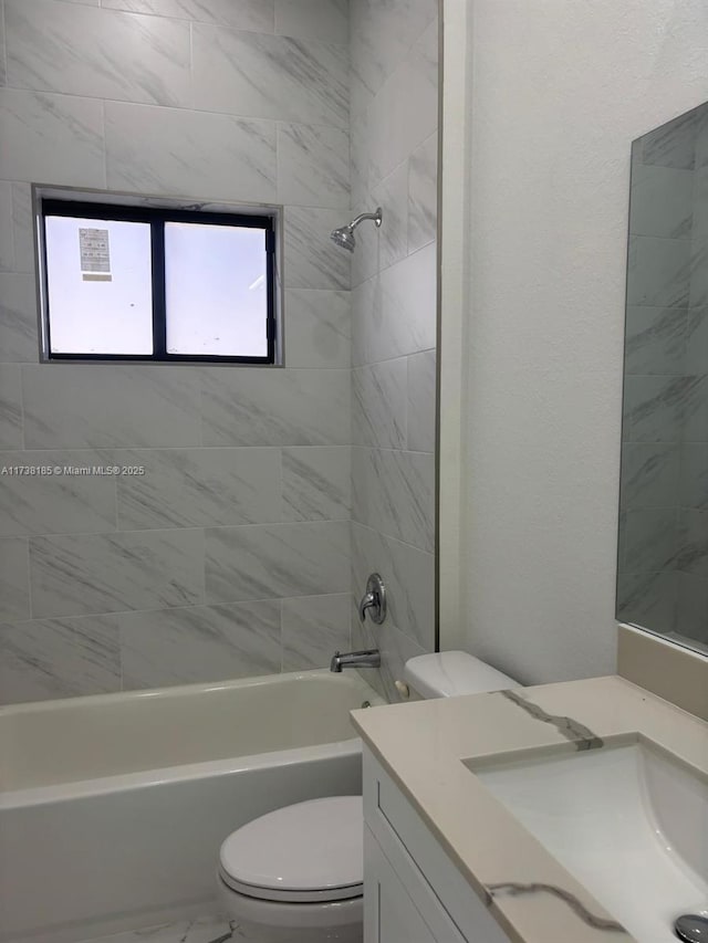 full bathroom with tiled shower / bath, vanity, and toilet