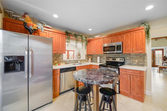 kitchen with stainless steel appliances, a breakfast bar, sink, and backsplash