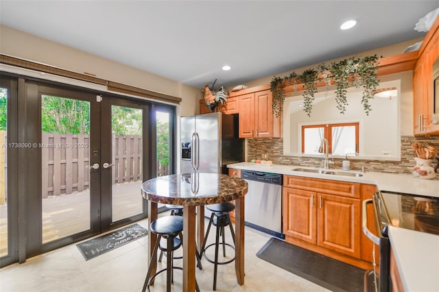 kitchen with sink, a kitchen breakfast bar, stainless steel appliances, tasteful backsplash, and french doors