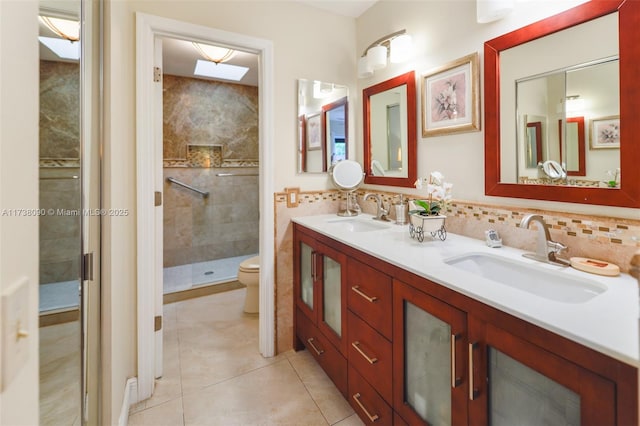 bathroom featuring backsplash, vanity, toilet, a shower with door, and tile patterned floors