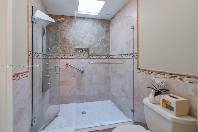 bathroom featuring an enclosed shower, toilet, a skylight, and tile walls