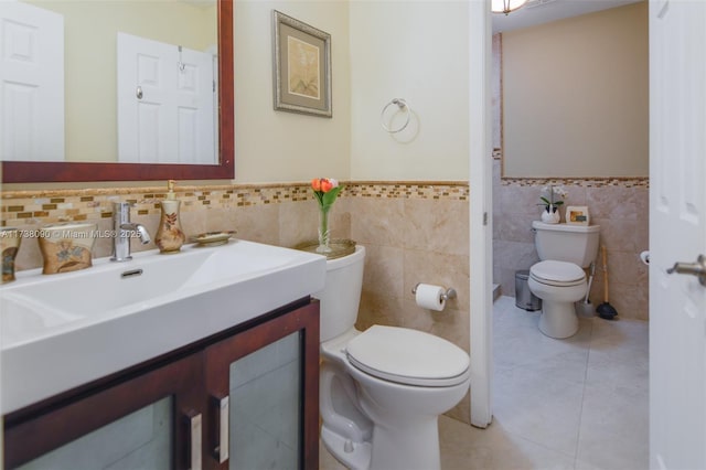 bathroom with tile patterned flooring, vanity, tile walls, and toilet