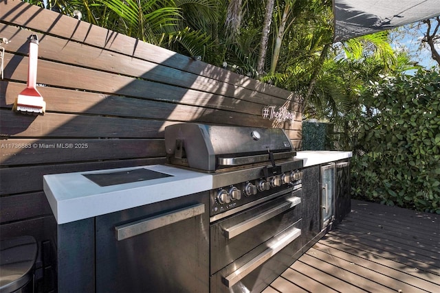 wooden deck with area for grilling and an outdoor kitchen