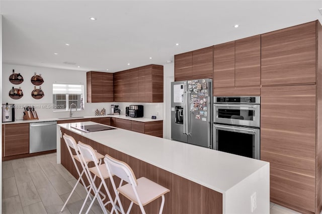 kitchen with sink, a breakfast bar area, and appliances with stainless steel finishes