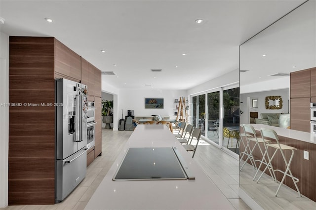 kitchen with a breakfast bar area, high end refrigerator, and light hardwood / wood-style floors