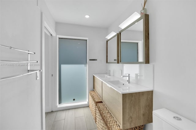 bathroom with walk in shower, vanity, and toilet