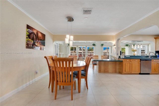 dining area with crown molding, a wealth of natural light, a notable chandelier, and light tile patterned floors