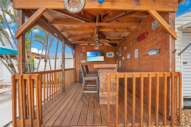 wooden deck with a bar and ceiling fan