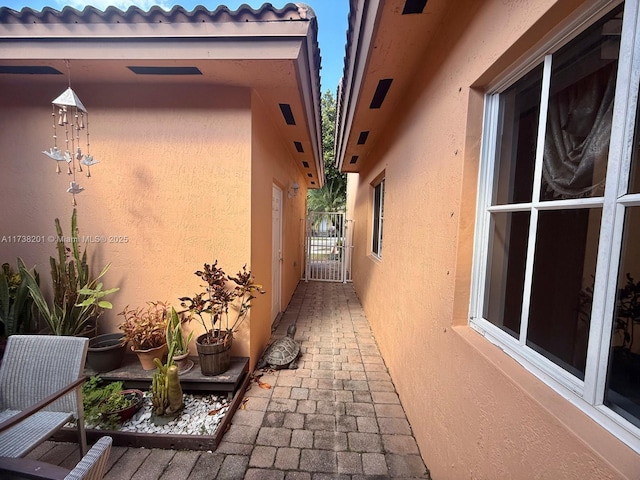 view of home's exterior with a tile roof, a gate, and stucco siding