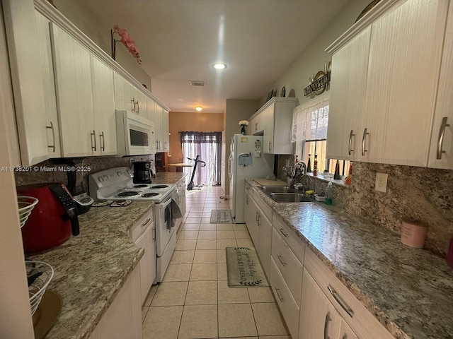 kitchen with light tile patterned floors, tasteful backsplash, visible vents, a sink, and white appliances