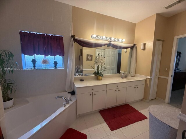 bathroom with tile patterned flooring, vanity, and a bath