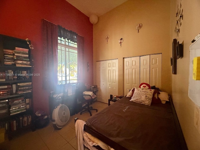 bedroom featuring tile patterned flooring, high vaulted ceiling, and multiple closets