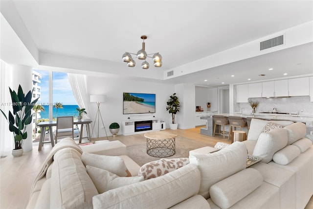 living room featuring a notable chandelier, light hardwood / wood-style floors, and sink