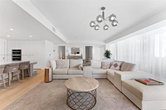 living room with a wealth of natural light, light hardwood / wood-style floors, and a chandelier