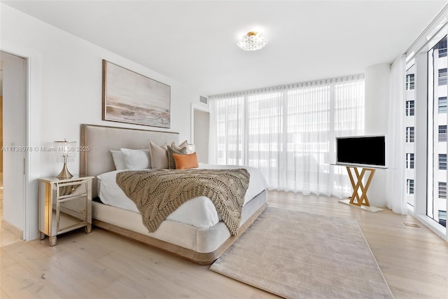 bedroom featuring a wall of windows and light wood-type flooring