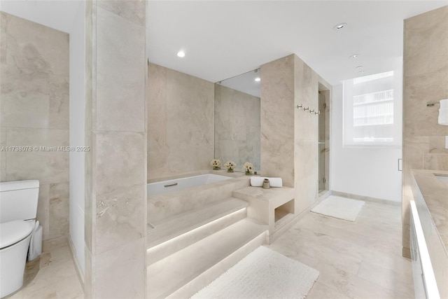 bathroom featuring toilet, independent shower and bath, and tile walls