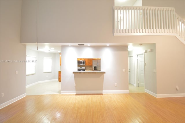 unfurnished living room with a towering ceiling and light wood-type flooring