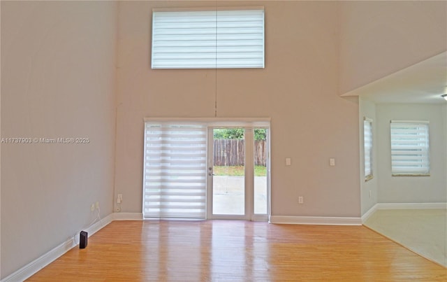 empty room with light hardwood / wood-style flooring and a high ceiling