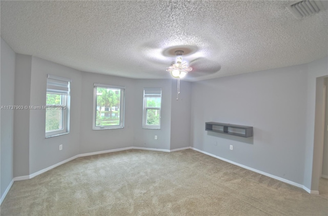 unfurnished room featuring ceiling fan, light colored carpet, and a textured ceiling