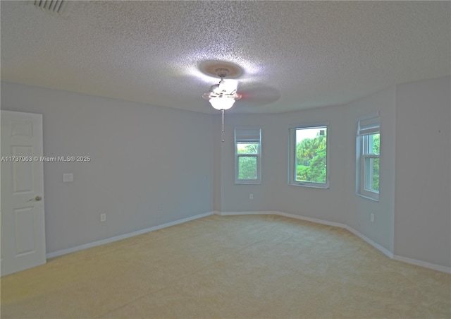 unfurnished room with light colored carpet and a textured ceiling